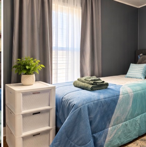 Bed with fresh towels beside a bedside storage drawer and plant
