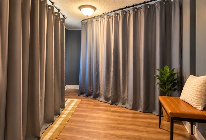 Room divided by floor-to-ceiling privacy curtains, with a bench seat